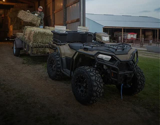Utility ATV towing a hay trailer on a farm