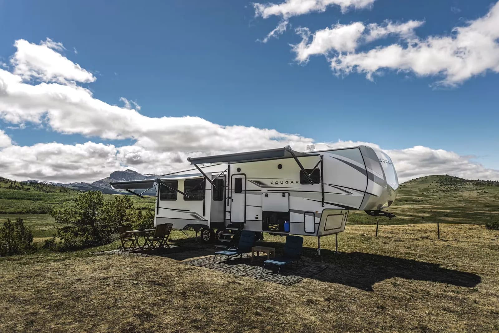 Travel trailer camped on a grassy ridge under a big sky